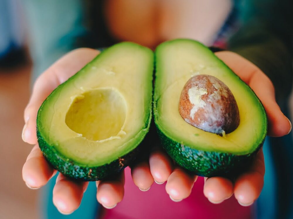 hands holding sliced avocado