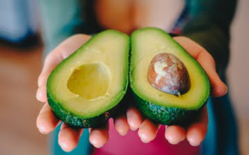 hands holding sliced avocado