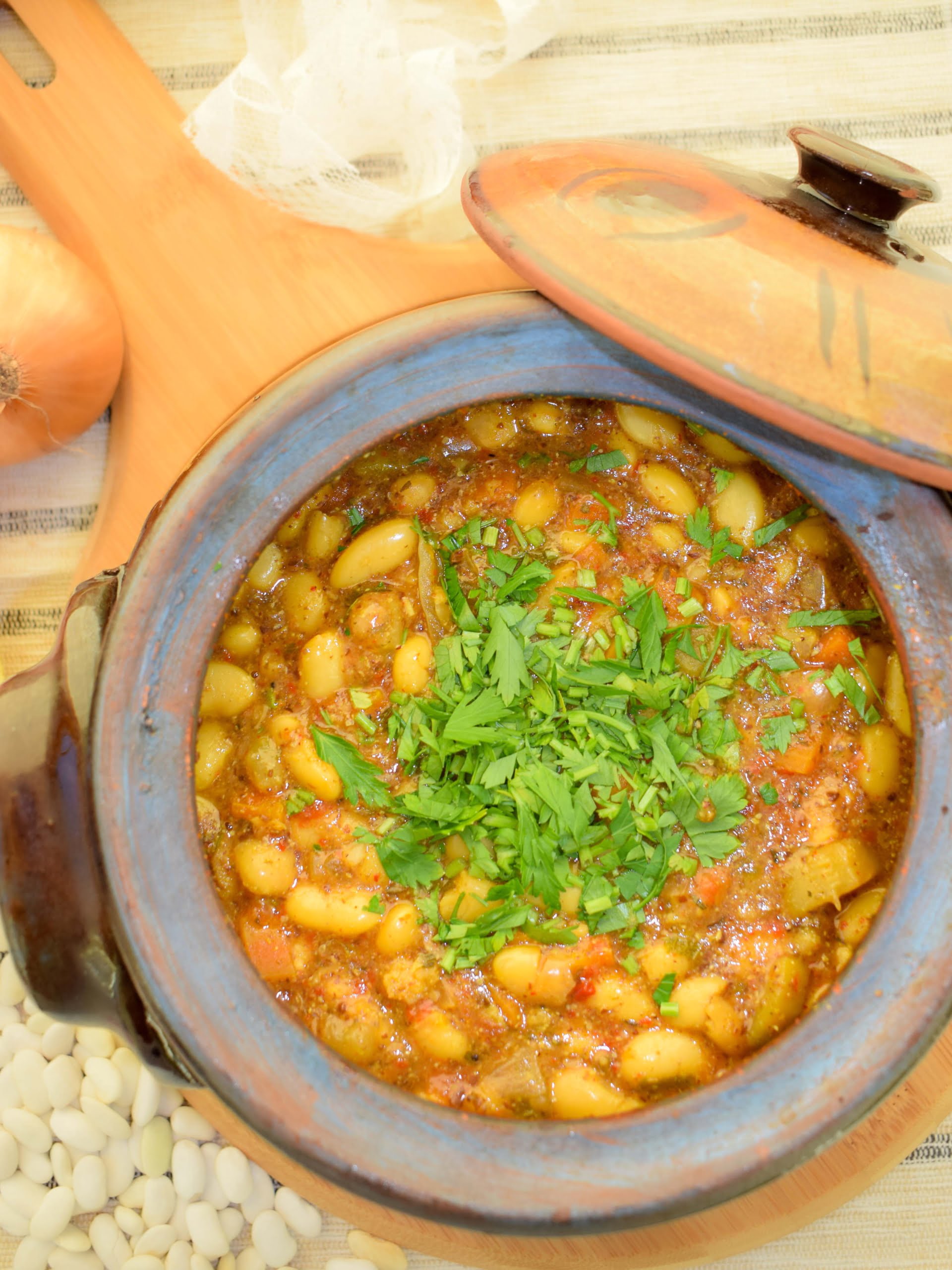 Rich vegan baked beans with vegetables in a clay pot