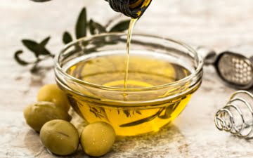 a bowl full of olive oil and some olives