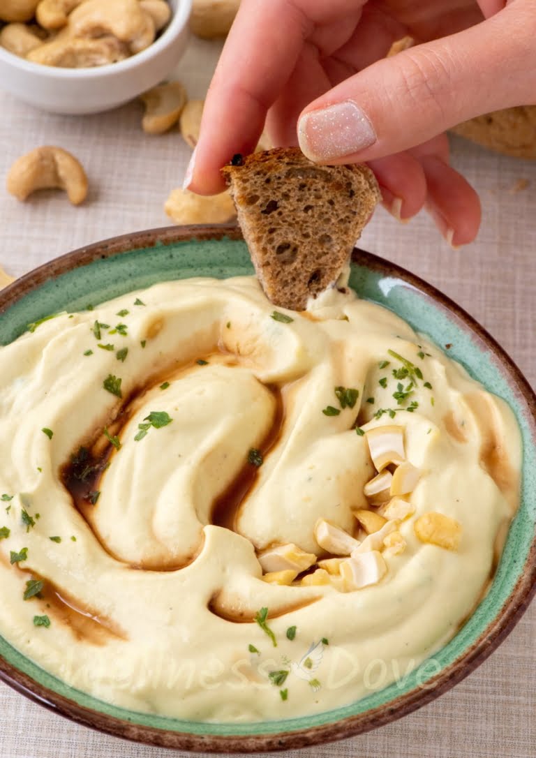 The vegan zucchini spread, a hand dipping some bread in