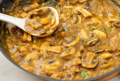 Curry mushrooms simmering in a pan, served over white bean mash
