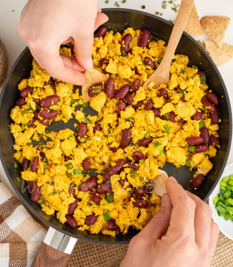 overhead view, two hands dipping bread in the scramble