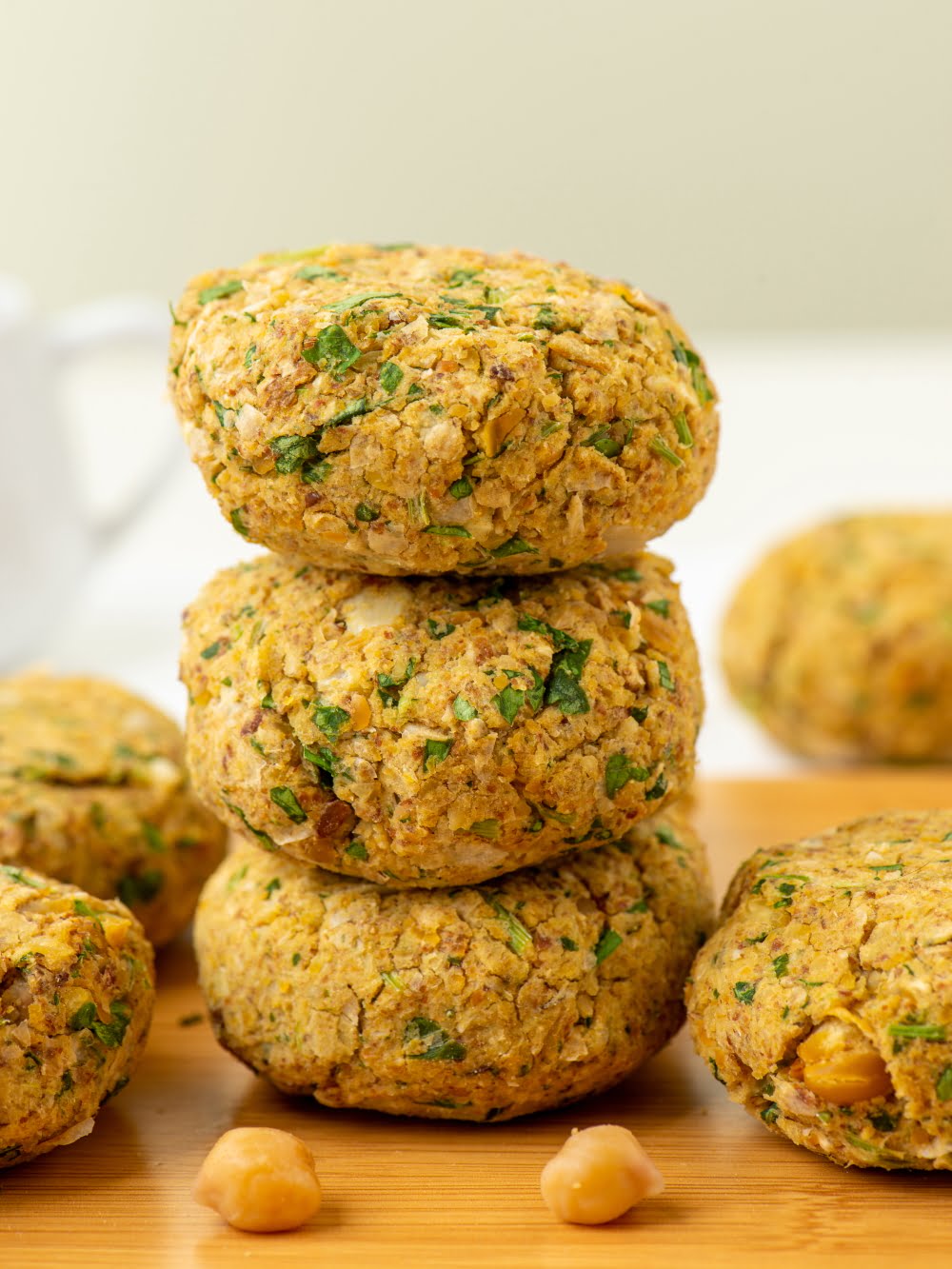 Stack of baked falafel patties with chickpeas on a wooden board