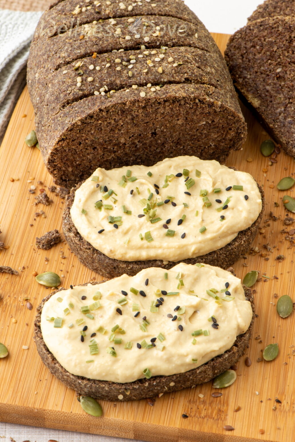 a couple of slices of the vegan gluten free seeds bread with hummus on top of them
