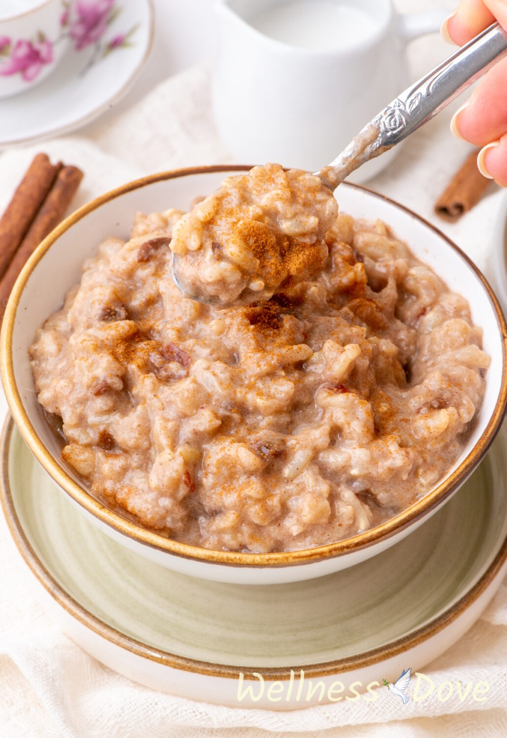 the  quick vegan brown rice pudding in a white bowl and a hand is taking some of it out with a spoon