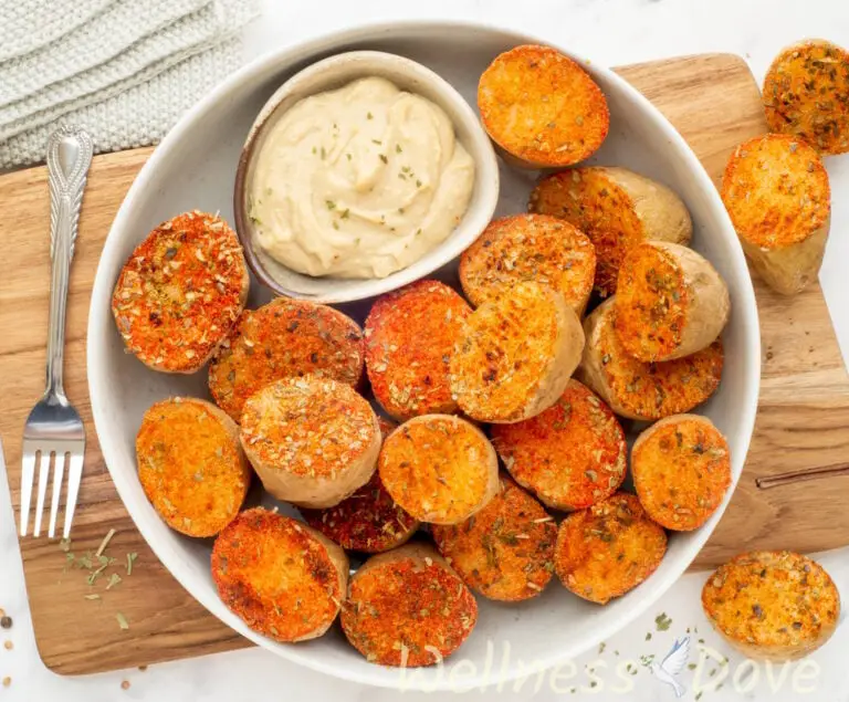 the the vegan oven baked potatoes with herbs in a bowl with some hummus on the side, 3/4 angle