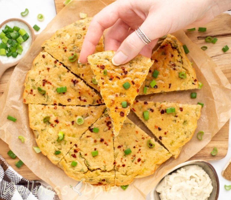 an overhead view of the easy gluten free chickpea flatbread while a hand is showing a piece to the camera