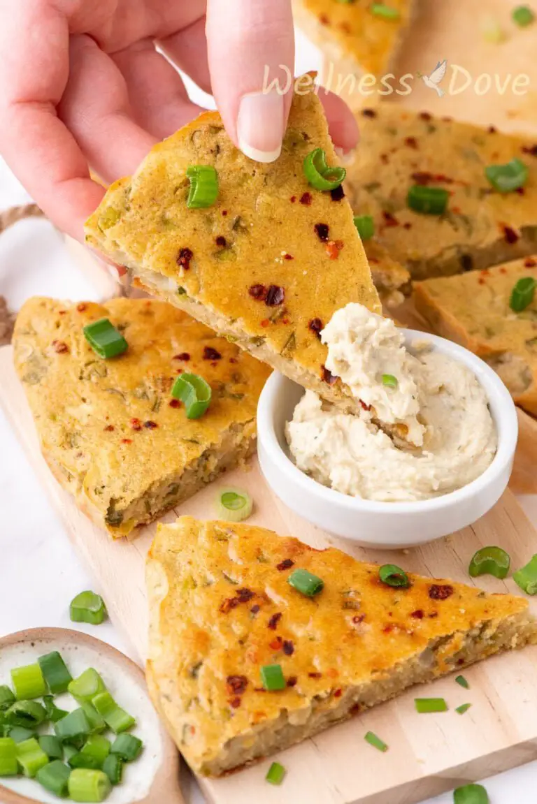 a hand is dipping a piece of the easy gluten free chickpea flatbread in some hummus