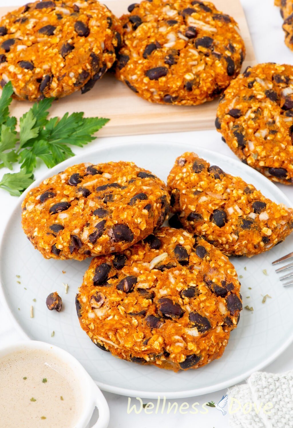 three of the Sweet Potato Black Bean Burgers are in a plate and another three are on a chopping board next to them.