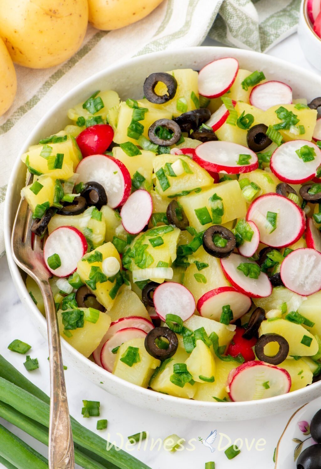 close up view of the vegan no mayo potato salad in a large bowl, with a fork in the bowl