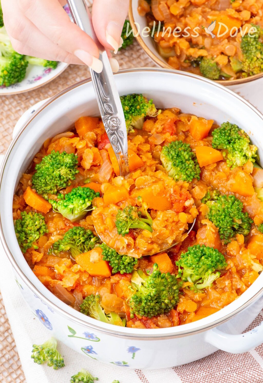 the Quick Broccoli Red Lentil Vegan Soup in  a pot while a hand is taking some out with a laddle