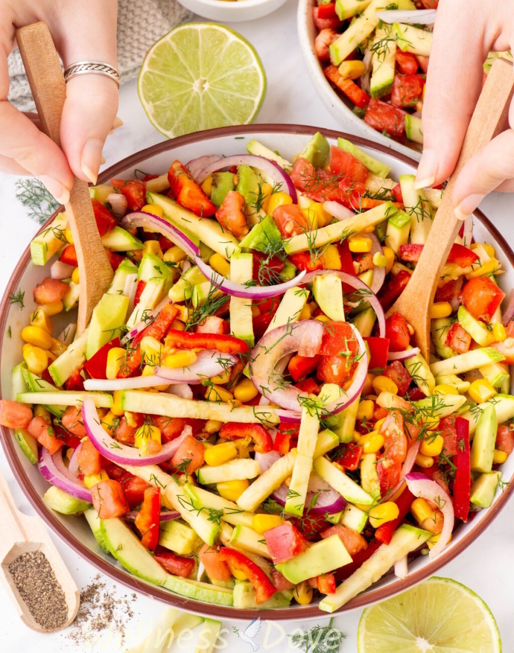 the Zucchini Vegan Salad in a bowl while to hands are tossing it 