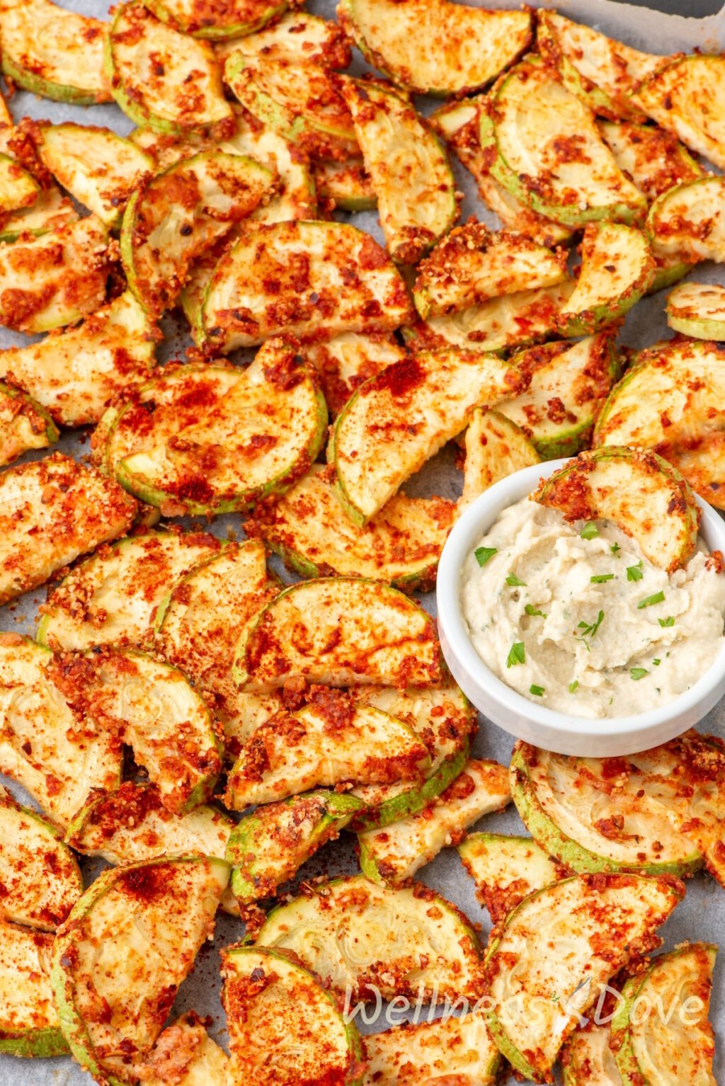 close up shot of the Easy Oil-free Vegan Baked Zucchini while still in the baking tray with some hummus