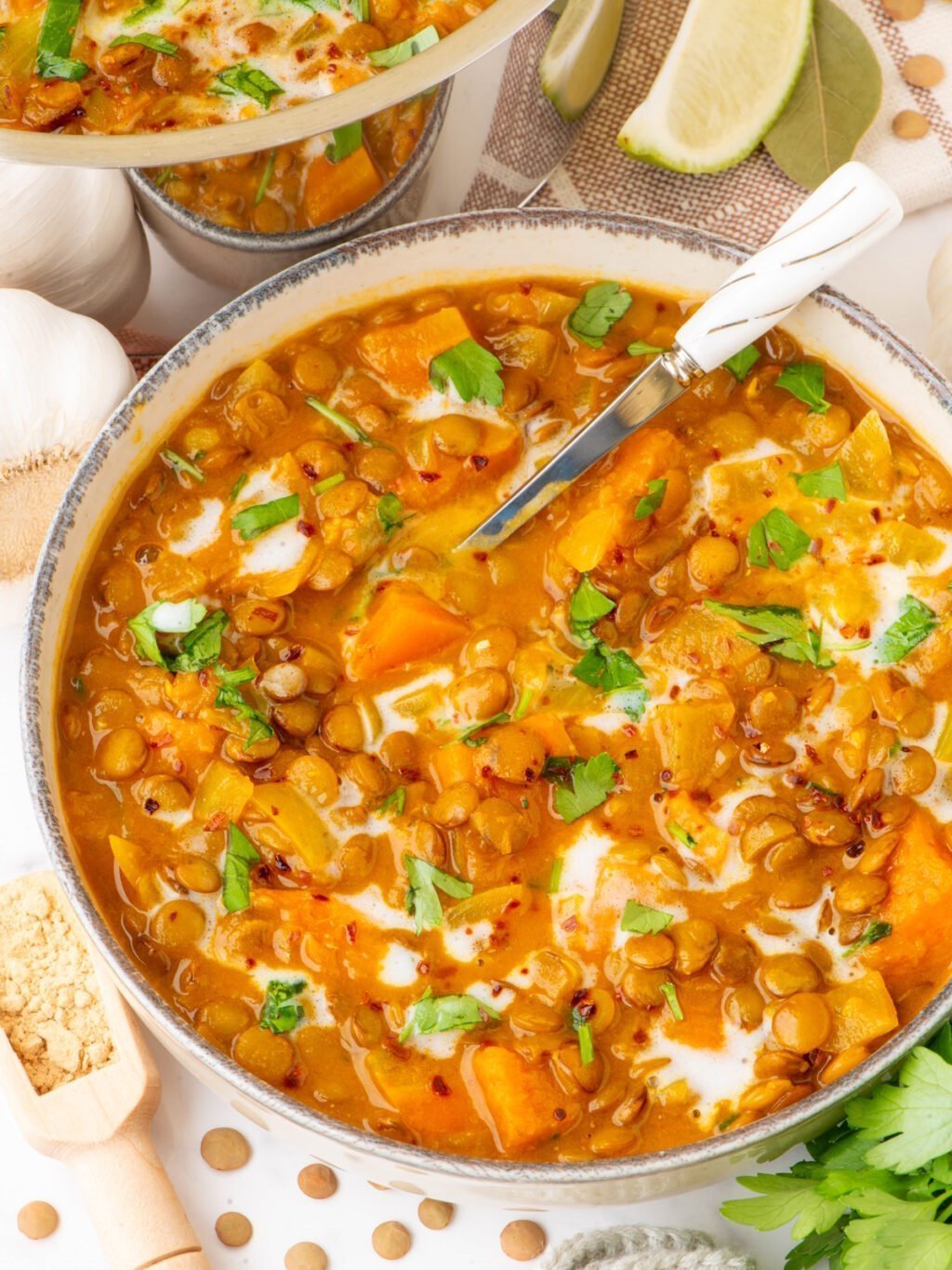 Sweet potato and lentil curry in a pot, topped with fresh herbs