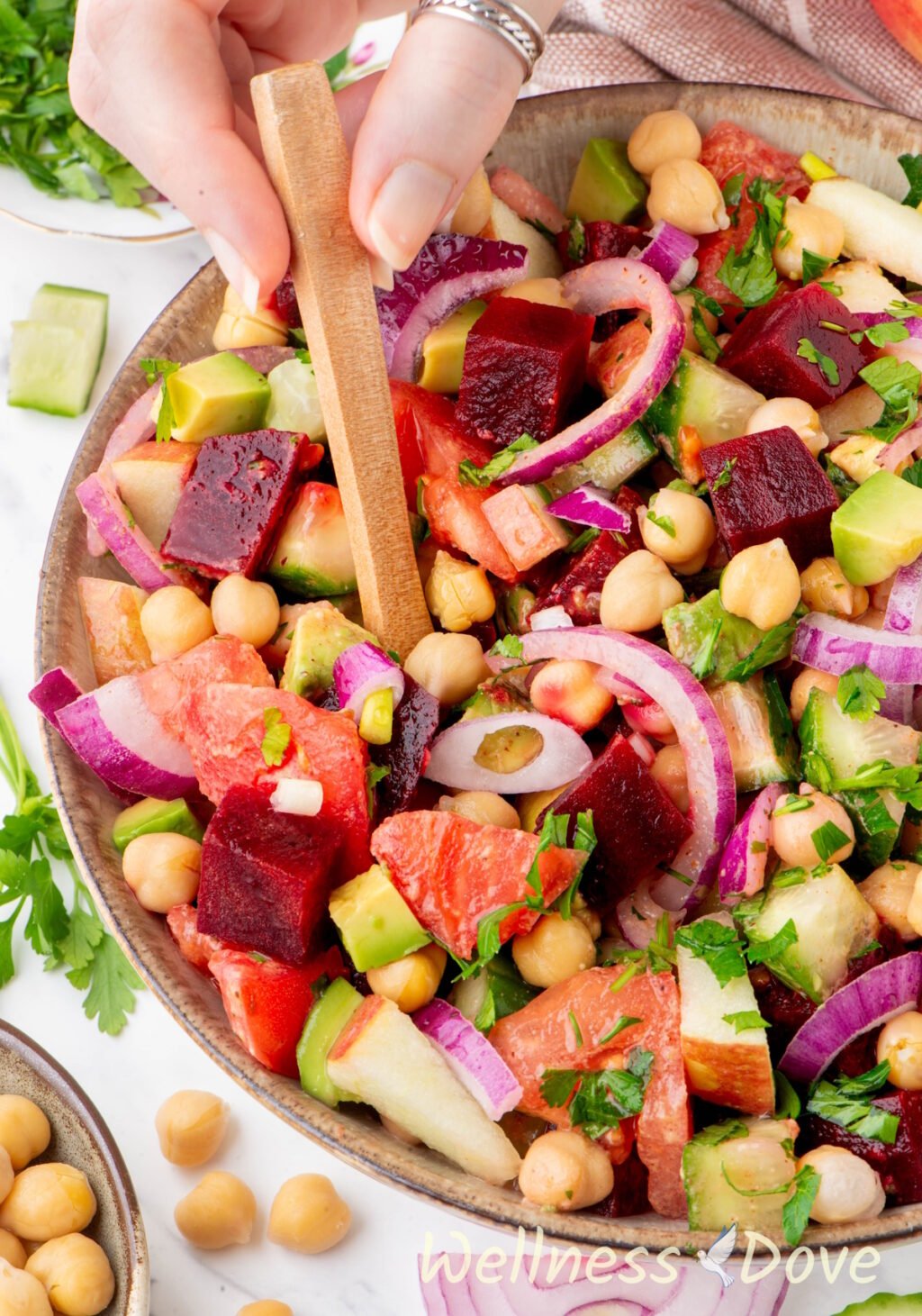 a macro photo of the Easy Vegan Chickpea Beet Oil-free Saladin a bowl while a hand is taking some out with a spoon