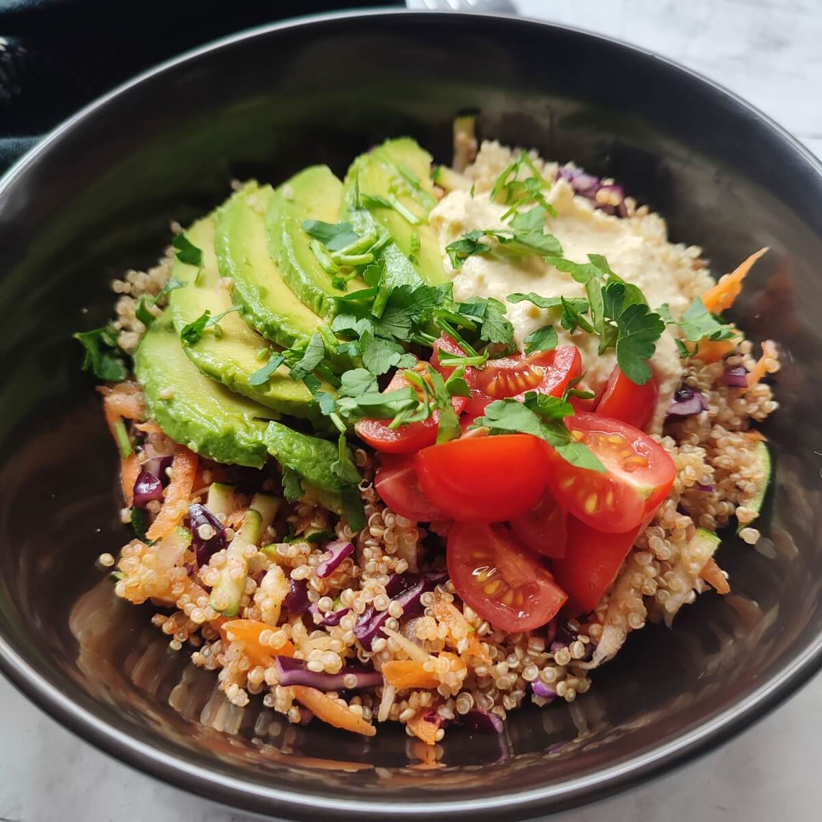 Savory quinoa breakfast bowl with avocado and raw vegetables
